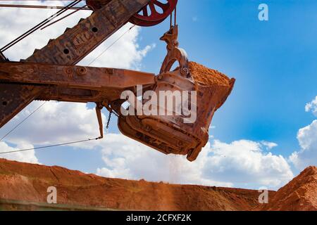 Arkalyk/Kazakhstan - Maggio 15 2012: Estrazione e trasporto di minerali di alluminio. Cava di argilla bauxite. Caricamento del treno auto con tramoggia. Primo piano della benna dell'escavatore. Foto Stock