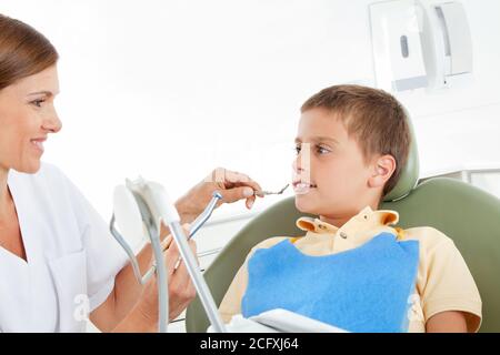 Bambino che riceve un trattamento da un dentista sorridente Foto Stock