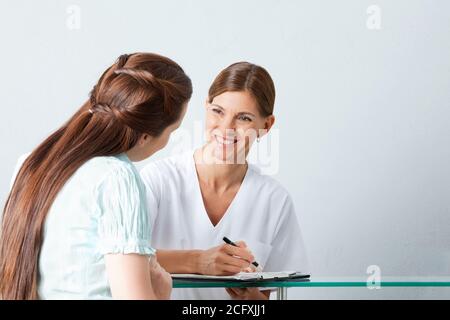 Il medico sorridente compila il questionario con un paziente Foto Stock