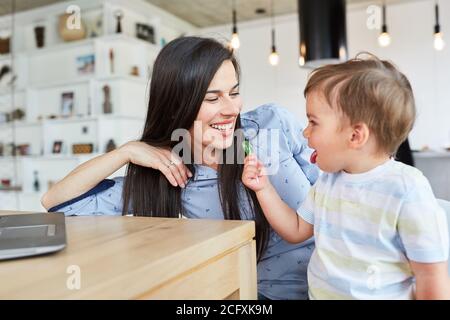 Felice madre e figlio con lollipop sul computer portatile in soggiorno Foto Stock