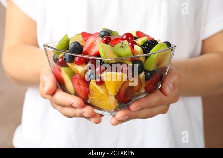 La donna tiene una ciotola di Macedonia di frutta fresca, vista frontale Foto Stock