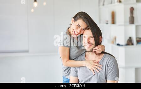 Giovane donna che si fooling intorno con i suoi capelli lunghi mentre taglia capelli per suo marito Foto Stock