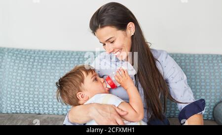 La madre felice dà al bambino il biberon del latte come concetto per amore e cura Foto Stock