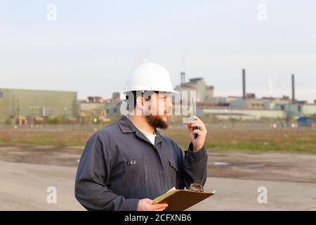 Ritratto di ingegnere maschile in piedi sul cantiere e tenendo carte. Foto Stock
