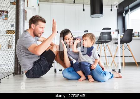 Genitori e figli si danno a vicenda un alto cinque giocare nel soggiorno Foto Stock
