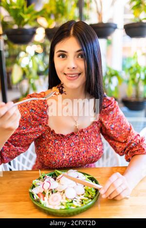 Donna sorridente mangiare insalata fresca nel ristorante Foto Stock