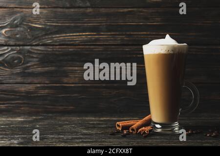 Bicchiere di latte, semi di caffè e cannella su fondo di legno Foto Stock