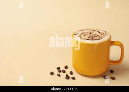 Tazza di latte e semi di caffè su sfondo beige Foto Stock