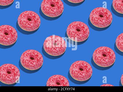 Deliziose ciambelle gustose con glassa rosa e Sprinkles rossi oltre Sfondo blu Foto Stock