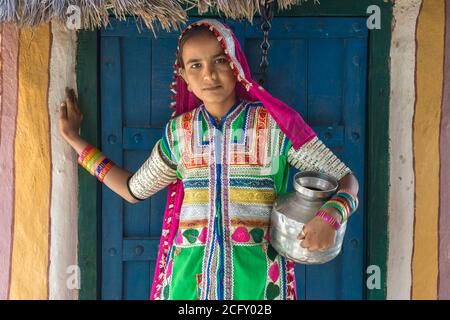 Ragazza in stoffa tradizionale in piedi di fronte a una casa, Khavda villaggio turistico, grande Rann di Kutch deserto, Gujarat, India Foto Stock