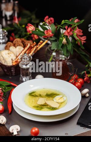 Una ciotola bianca piena di deliziosa zuppa di noodle di pollo Foto Stock