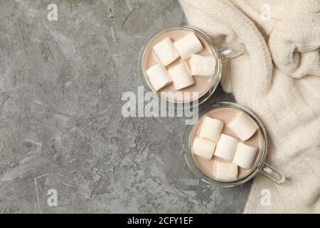 Maglione e tazze di caffè con marshmallows su sfondo grigio Foto Stock