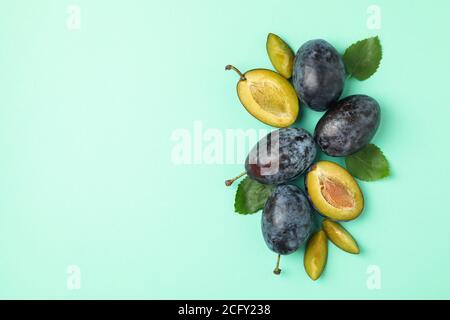 Prugne fresche e foglie su sfondo menta, vista dall'alto Foto Stock