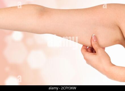 Donna che tiene la mano con grasso in eccesso contro un astratto sfondo con luci svasate e copyspace Foto Stock