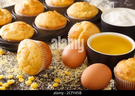 Muffin di mais tradizionali in una teglia da forno e ingredienti da vicino sul tavolo. Orizzontale Foto Stock
