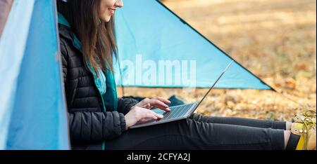 Closeup di ragazza irriconoscibile utilizzando il computer portatile in foresta Foto Stock