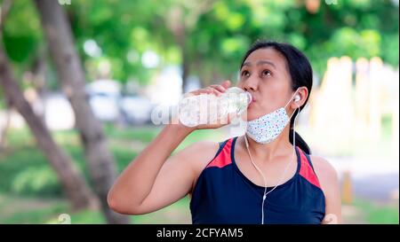 Ritratto delle donne asiatiche che bevono acqua pura dopo aver fatto jogging il parco Foto Stock