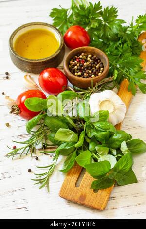 Ingredienti per cucinare. Erbe spezie, olio d'oliva e verdure su un tavolo di legno. Foto Stock