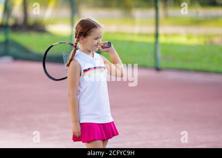 Bambino gioca a tennis sulla corte interna. Bambina con la racchetta e la palla in sport club. Esercizio attivo per i bambini. Attività estive per bambini. Foto Stock