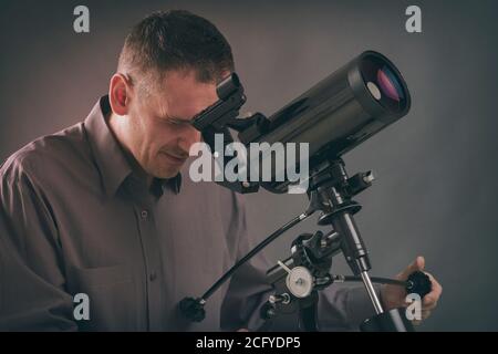 Uomo che guarda in cielo attraverso il telescopio astronomico Foto Stock