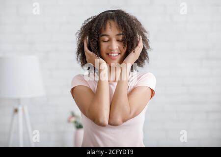 Donna afroamericana con occhi chiusi e cuffie in vita interno della camera Foto Stock