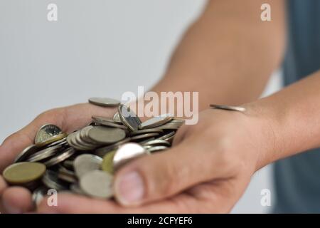 Monete in due mani. Concetto di risparmio di denaro. Foto Stock