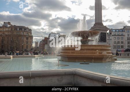 Una grande fontana e un bacino sono visti su Trafalgar Square London con la colonna di Nelson e l'edificio sullo sfondo. Foto Stock