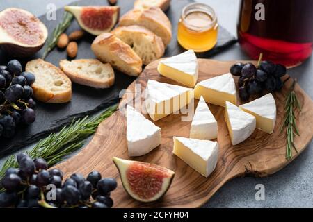 Formaggio Camambert con fichi, uva, miele e vino. Cibo gourmet, antipasto piatto di formaggio Foto Stock