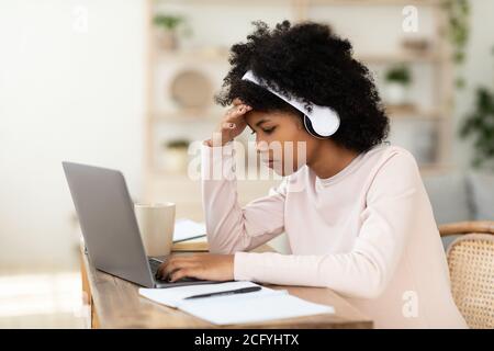 Ragazza al laptop fare lavoro a casa online, indossando auricolari Foto Stock