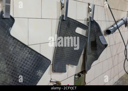 Tappetini in gomma sporchi appesi prima della pulizia primo piano tappetino sporco nella vettura Foto Stock
