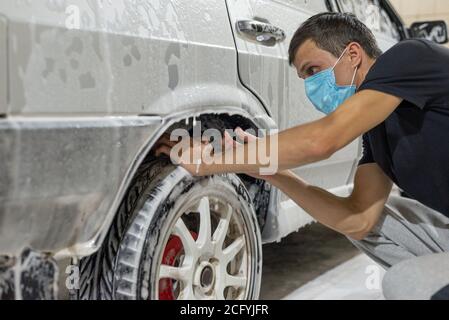 coronavirus pulizia della macchina, lavando la carrozzeria con un pulitore da soluzione di sapone. Il lavoro di tecnici automatici durante il periodo di quarantena COV Foto Stock