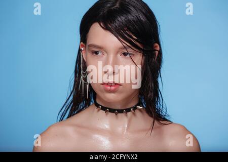 Ritratto di bella donna gotica con piercing e altri accessori in studio su sfondo bue. Emotivo, volto giovane. Emozioni umane, exp facciale Foto Stock