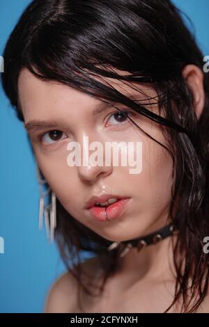 Ritratto di bella donna gotica con piercing e altri accessori in studio su sfondo bue. Emotivo, volto giovane. Emozioni umane, exp facciale Foto Stock