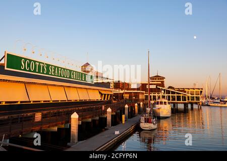 Jack London Square ormeggio e Scotts Seafood Grill al tramonto. Oakland, California, Stati Uniti Foto Stock