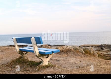 Una panchina blu vuota di fronte all'oceano atlantico in francese Bretagna Foto Stock