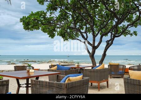 Vista sulla caffetteria Alfresco con intimi mobili in rattan e piumeria sulla terrazza della spiaggia sull'oceano. Foto Stock