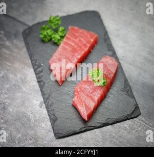 Filetto di tonno crudo su fondo di pietra nera Foto Stock