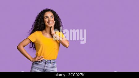 Offerta interessante. Pessive Asian Girl guardando da parte Copy Space su sfondo viola e giocosamente sorridente, Panorama Foto Stock