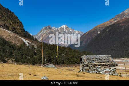 Un'immagine di fuoco selettiva di una capanna fatta di pietre Con bandiere di preghiera tibetane di fronte alla valle di Fiori in sikkim India Foto Stock