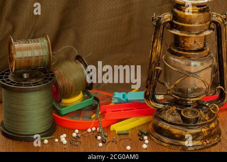 lenza da pesca, ganci, platine, attrezzi illuminati da un'antica lampada a cherosene Foto Stock