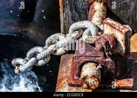 Primo piano immagine del vecchio bollard arrugginito con catena sul molo. Foto Stock