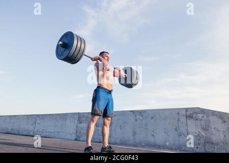 Montare il giovane uomo che solleva barbells cercando messo a fuoco, allenandosi. Foto Stock