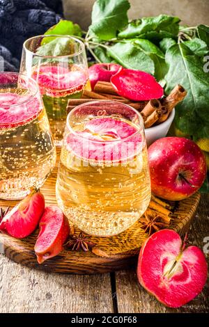 Bevanda di sidro di mela. Cocktail martini di sidro di mele rosse autunnali, con fette di mela e mele fresche a fette, spazio copia di sfondo in legno Foto Stock