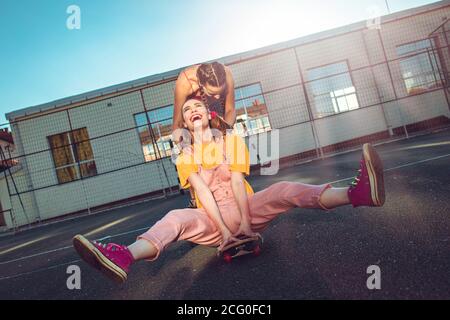 Due ragazze teen, amici che si divertono con skate board. Una ragazza spinge l'altra da dietro Foto Stock