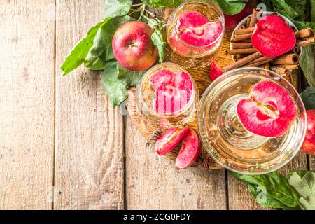 Bevanda di sidro di mela. Cocktail martini di sidro di mele rosse autunnali, con fette di mela e mele fresche a fette, spazio copia di sfondo in legno Foto Stock