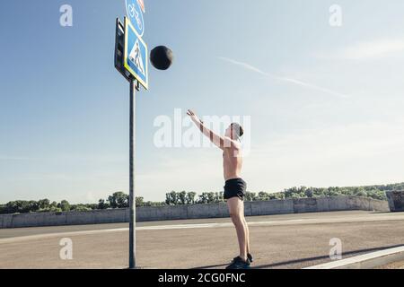 Allenamento di forza allenamento croce uomo allenamento gettando palla medica sulla parete palestra presso il centro fitness. Esercizi di pesi del corpo di workout usando la sfera pesante del peso. O Foto Stock