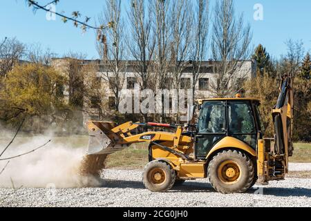 Dneprorudnoe/Ucraina - Aprile 08 2020: Un trattore versa la ghiaia dalla benna Foto Stock