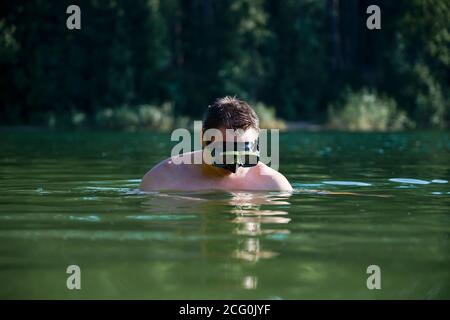 Un ragazzo in una maschera subacquea si tuffa dall'acqua Foto Stock