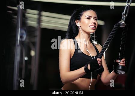 Sport donna facendo esercizio al crossover macchina in palestra Foto Stock