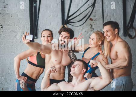 Gruppo di persone sportive in palestra che prendono selfie - Felici gli amici sportivi in una sala pesi durante l'allenamento - Concetti sullo stile di vita e lo sport in una fitne Foto Stock